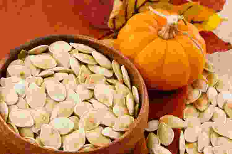 Toasted Pumpkin Seeds in bowl next to pumpkin