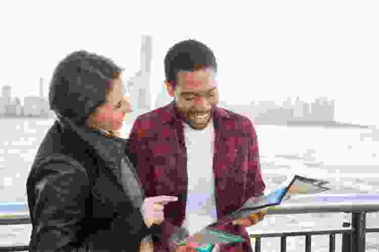 tourist couple looking at map by New York skyline