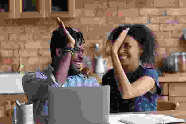 young couple high fiving in front of laptop