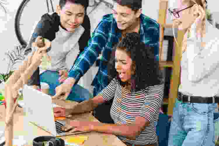 group of teens playing game on laptop