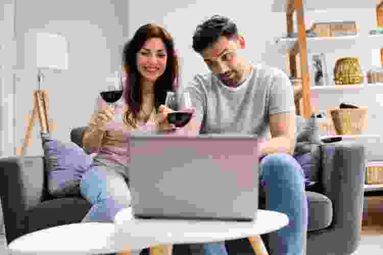 couple drinking wine and video calling on laptop