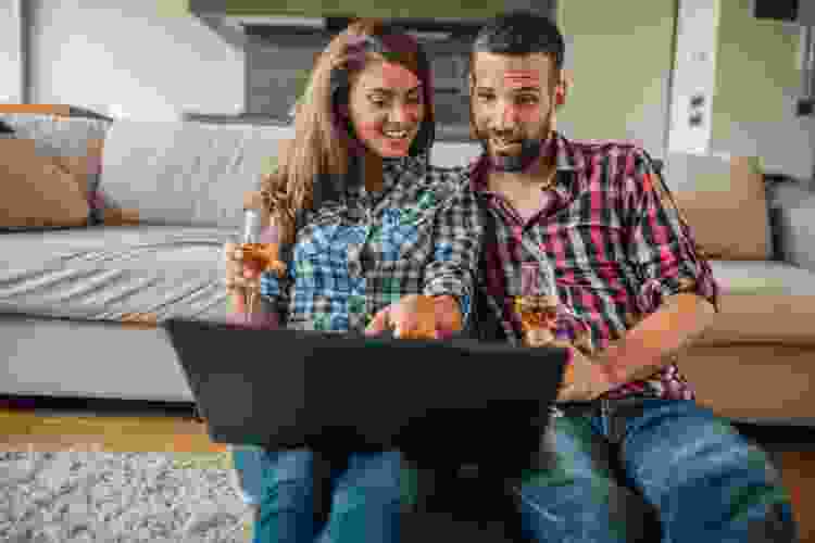 couple with laptop sampling small glass of wine