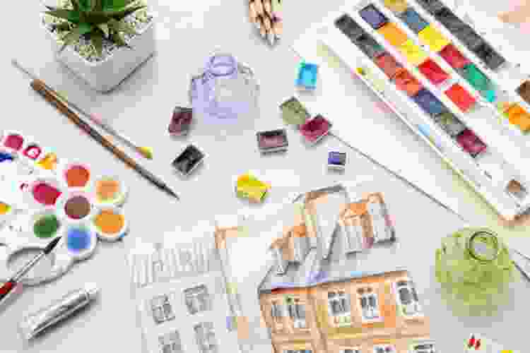 watercolor painting set and supplies scattered on table