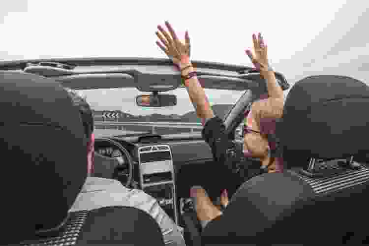 friends in convertible with hands in the air