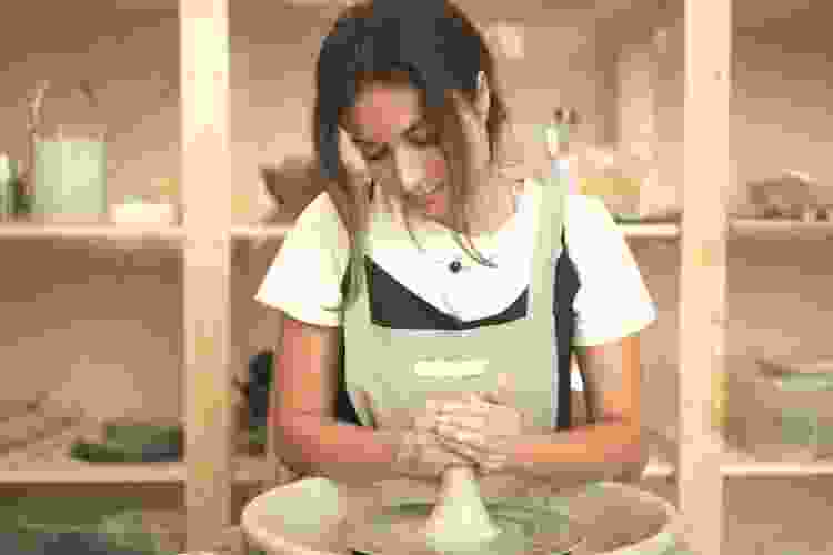 woman molding clay using a potters wheel