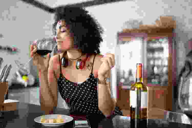 woman tasting wine at home listening to music