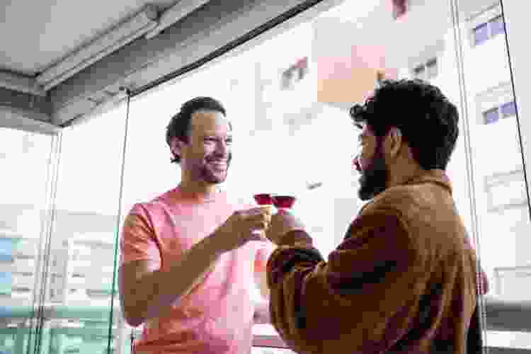 two men sipping wine together at home