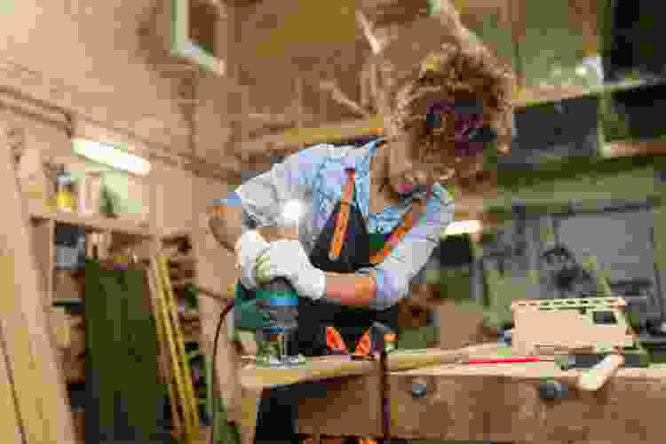 woman sawing wood in wood working class