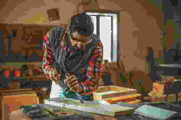 young man carving plank in woodshop