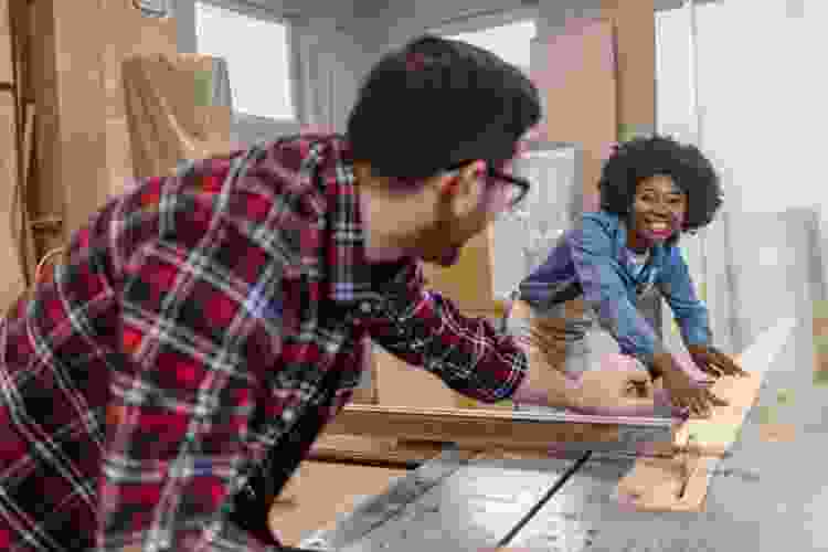 couple carving wood in woodshop together