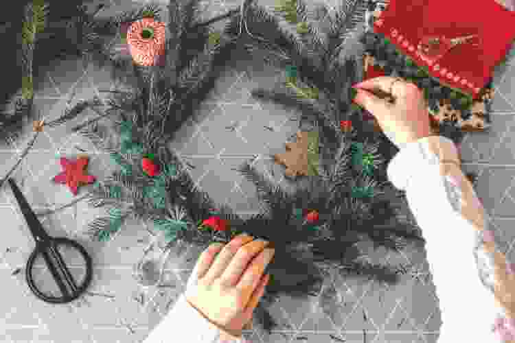 hands assembling holiday wreath