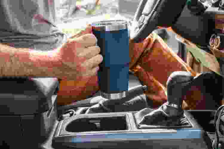 man driving car with YETI cup in hand