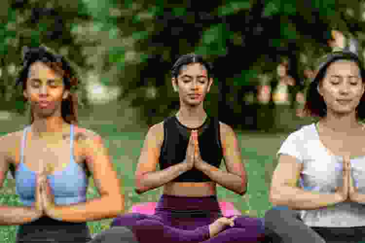 three women meditating in outdoor yoga session