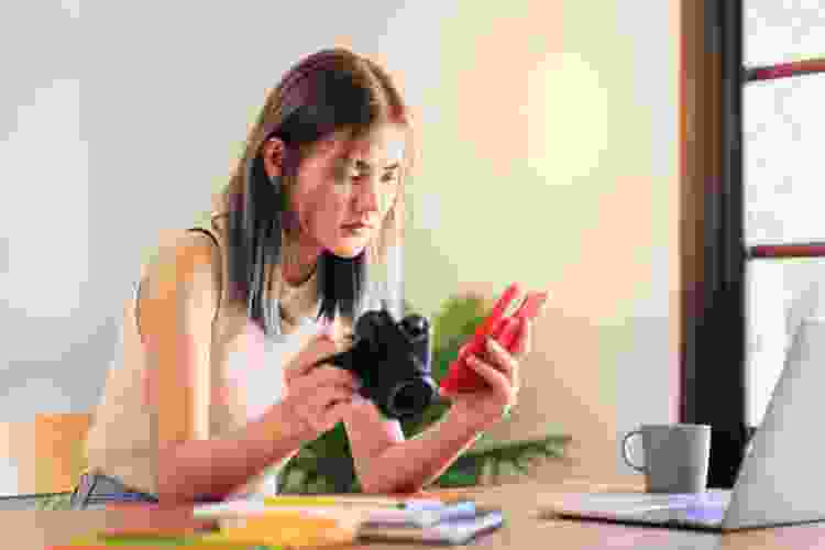 Young Asian woman looking at a camera and smartphone