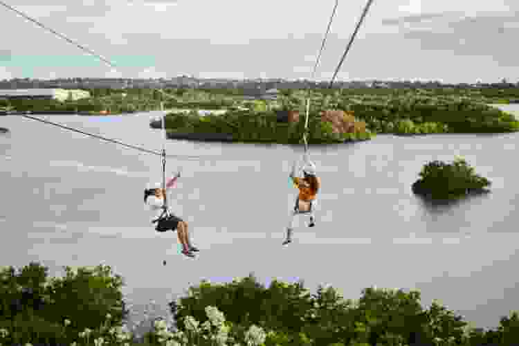 two women riding zip line over water