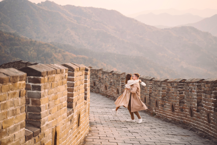 young couple running twirling great wall china