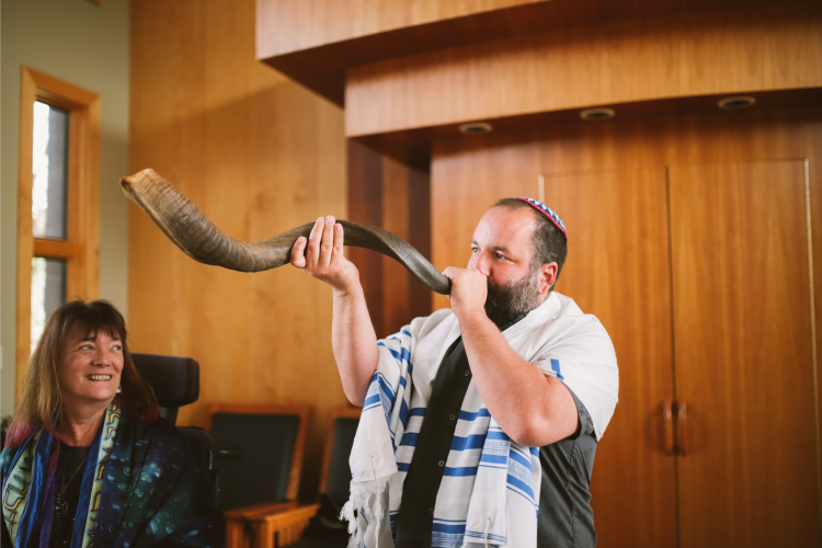 man blowing shofar in synagogue