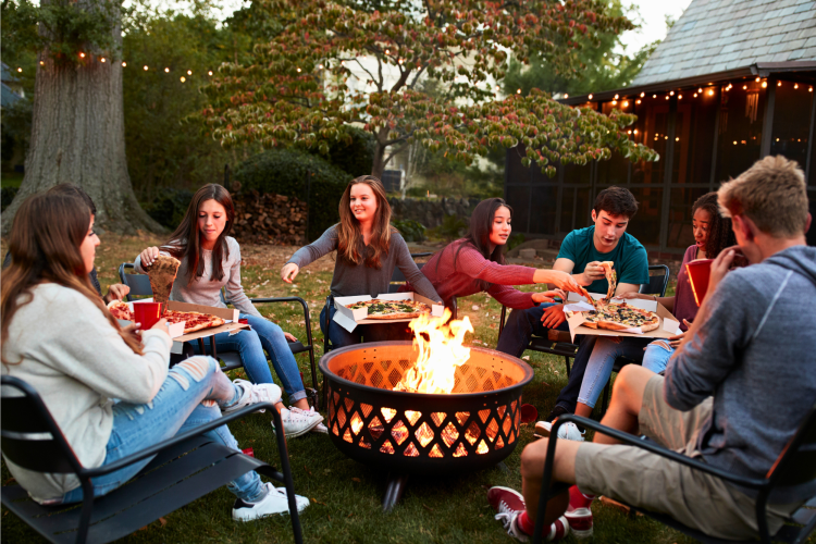 friends eating pizza around a fire pit