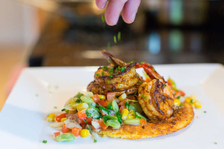 chef plating shrimp over grits