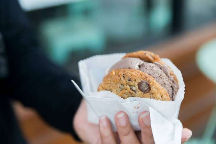 someone holding an ice cream cookie in a wax wrapper