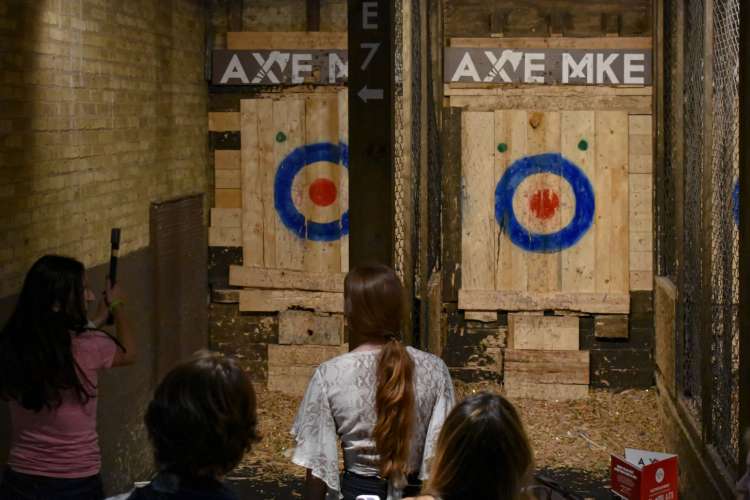 People looking at two wooden axe targets while a woman prepares to throw.