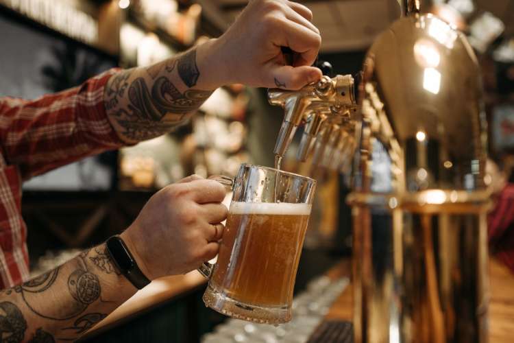 a bartender filling a beer glass from a draft at the bar