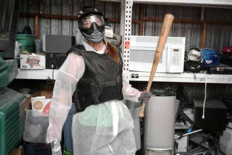 a woman in protective gear holding a bat in a roomful of appliances