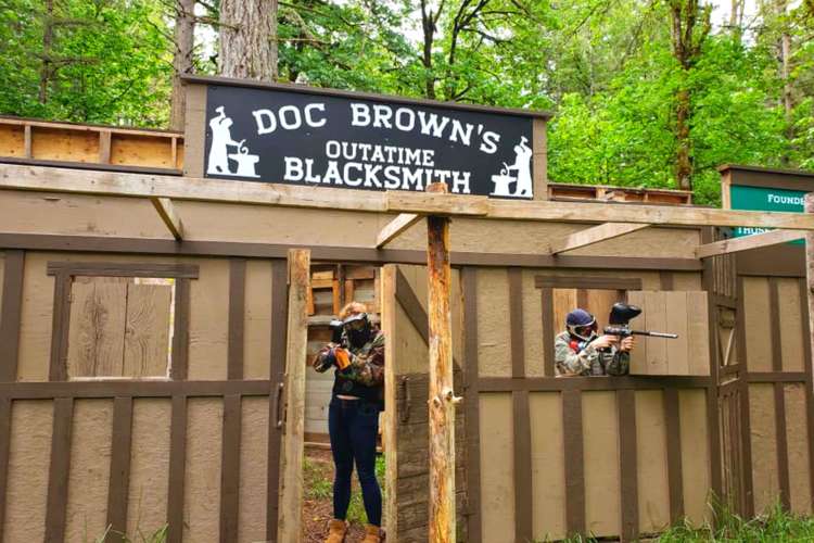 a paintballer hides in a wood frame reading Doc Brown's Outatime Blacksmith