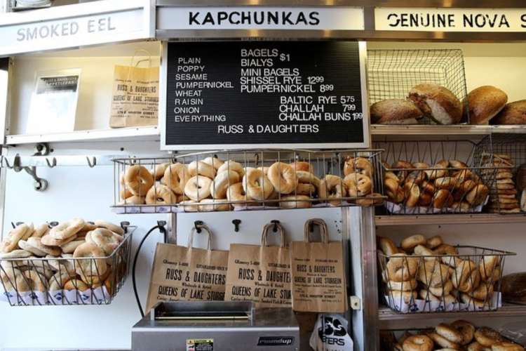 a counter displaying bagels, toppings, and a traditional menu