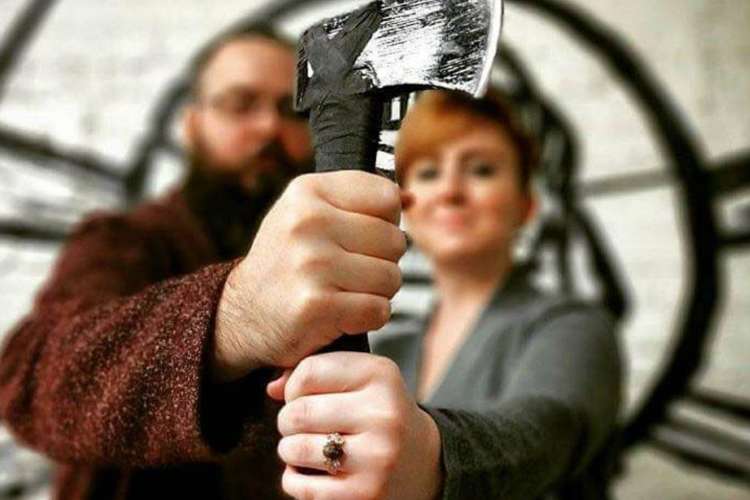 a man and woman hold the handle of an axe together