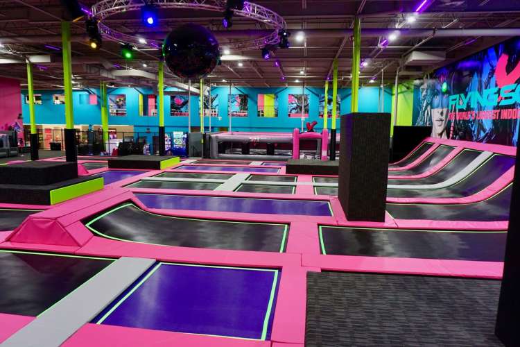 the pink, black and neon blue interior of a trampoline park