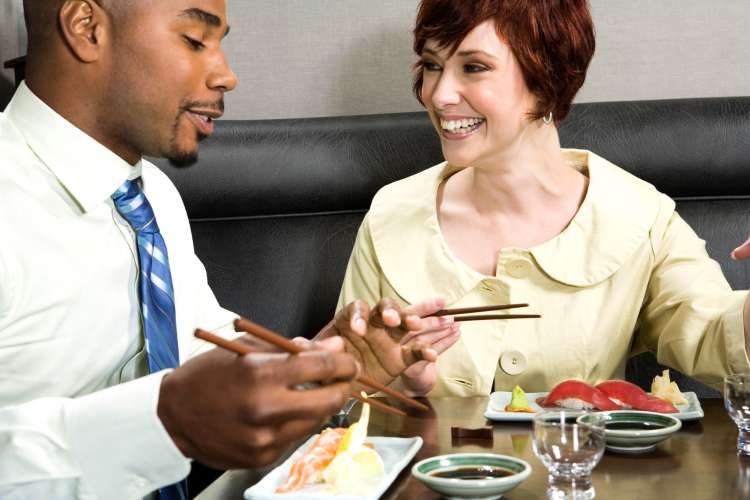 a smiling couple eating sushi in a restaurant