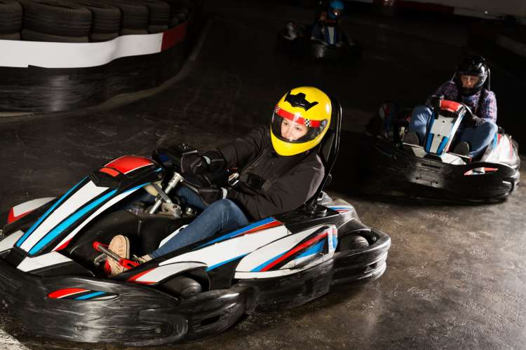 people in helmets driving go-karts indoors