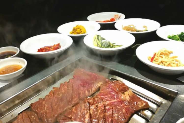 steaming barbecued Korean beef with kimchi and other sides