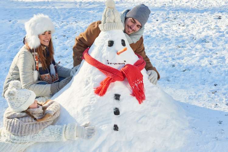 A man and woman building a snowman, which is a cute first date idea