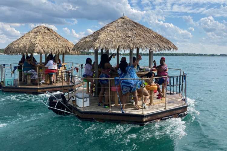 a group of floating tiki boats filled with happy guests