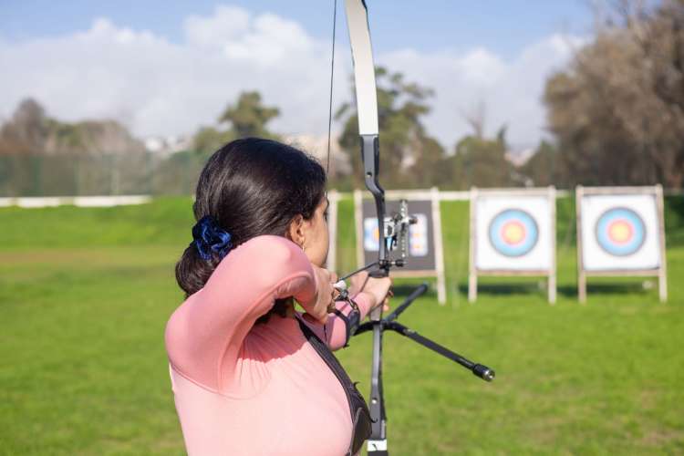 A woman takes aim with a bow and arrow