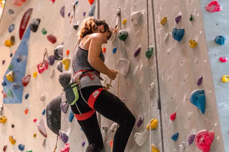 a woman using a climbing wall with a rope and harness