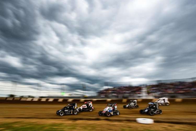 race cars zooming by on a cloudy day at the Indy Motor Speedway