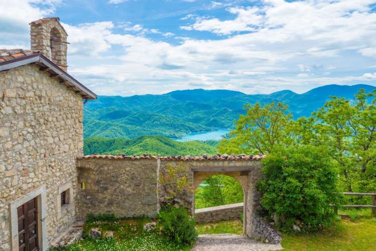 a stone house and gate against a crisp mountain scene