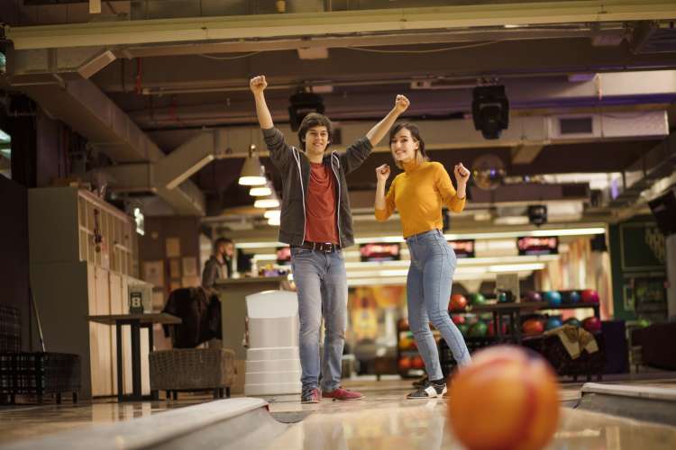 a couple at a bowling alley cheer each other on