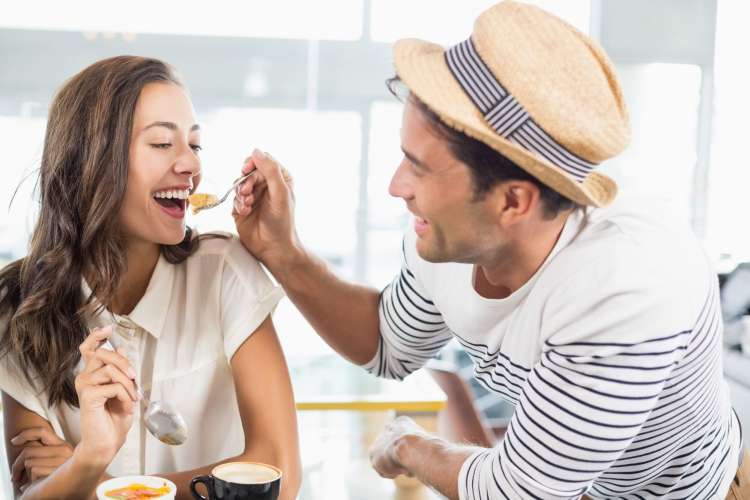 A man shares a bite of dessert with his dining partner, which is a cute first date idea