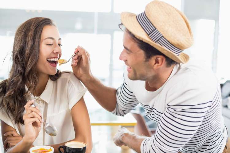 a man shares a bite of dessert with his dining partner