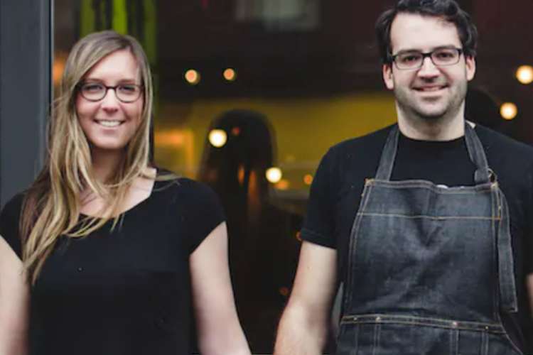 a young couple standing together in front of a pizza restaurant