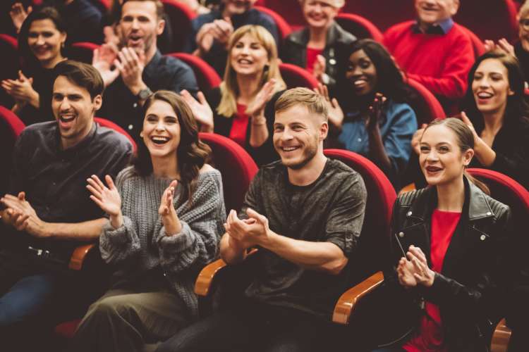 An audience applauding during a live show, which is a great one-year anniversary date idea