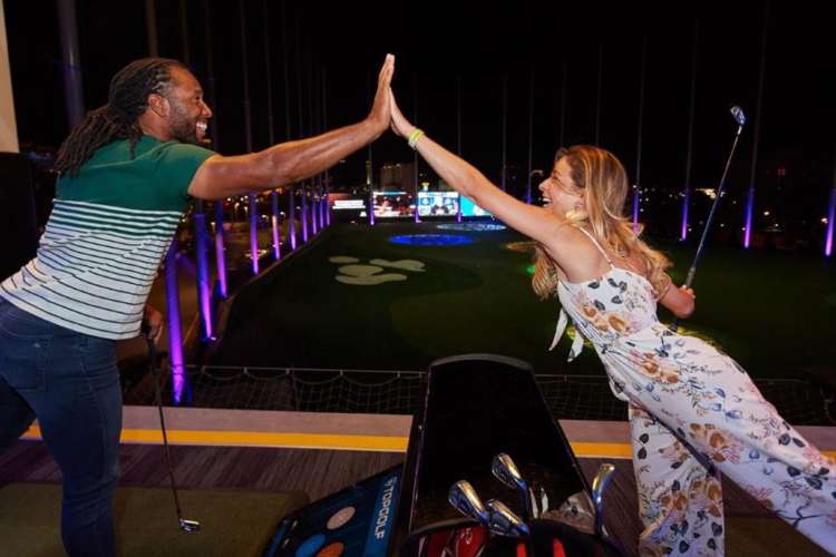 a man and woman give each other a high five at a TopGolf venue