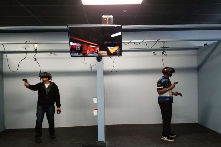 two men in VR headsets play a game in front of a TV screen