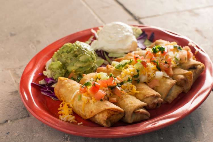 a platter of chimichangas with guacamole and sour cream