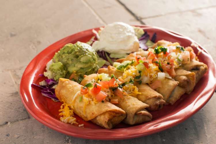 a platter of chimichangas with guacamole and sour cream