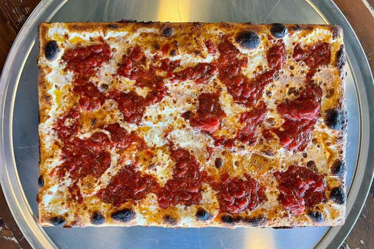 a square slice of pizza on a green plate